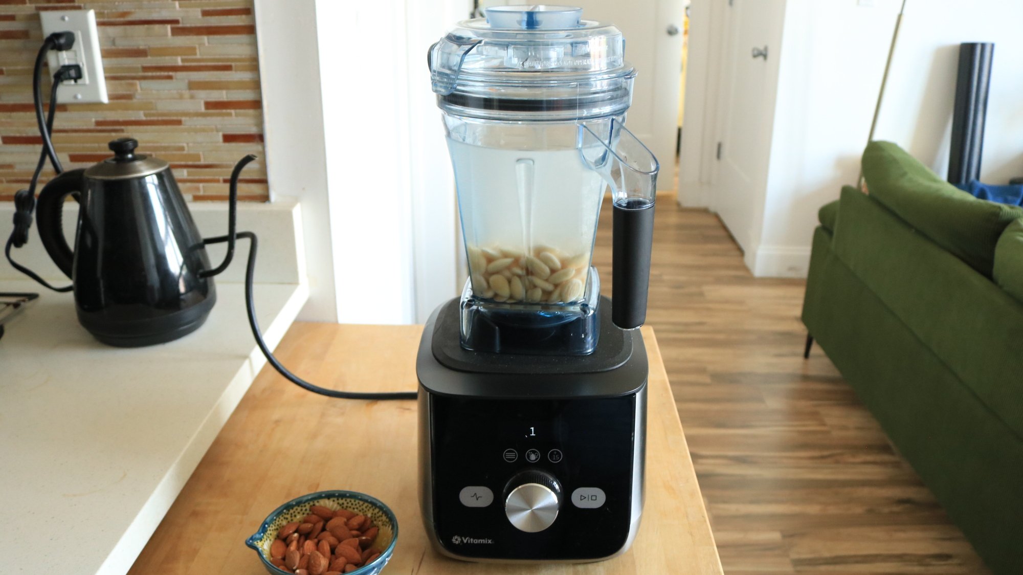 A Vitamix blender with nuts and water inside sitting on a countertop.