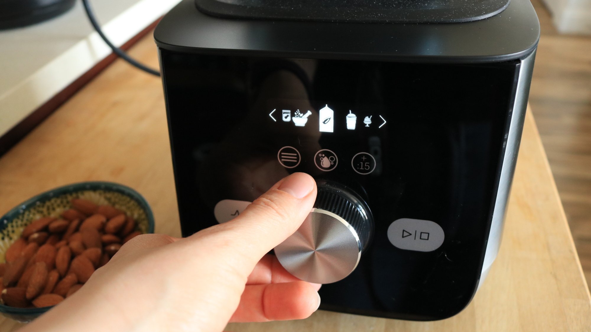 A person's hand turning the knob of a Vitamix machine.