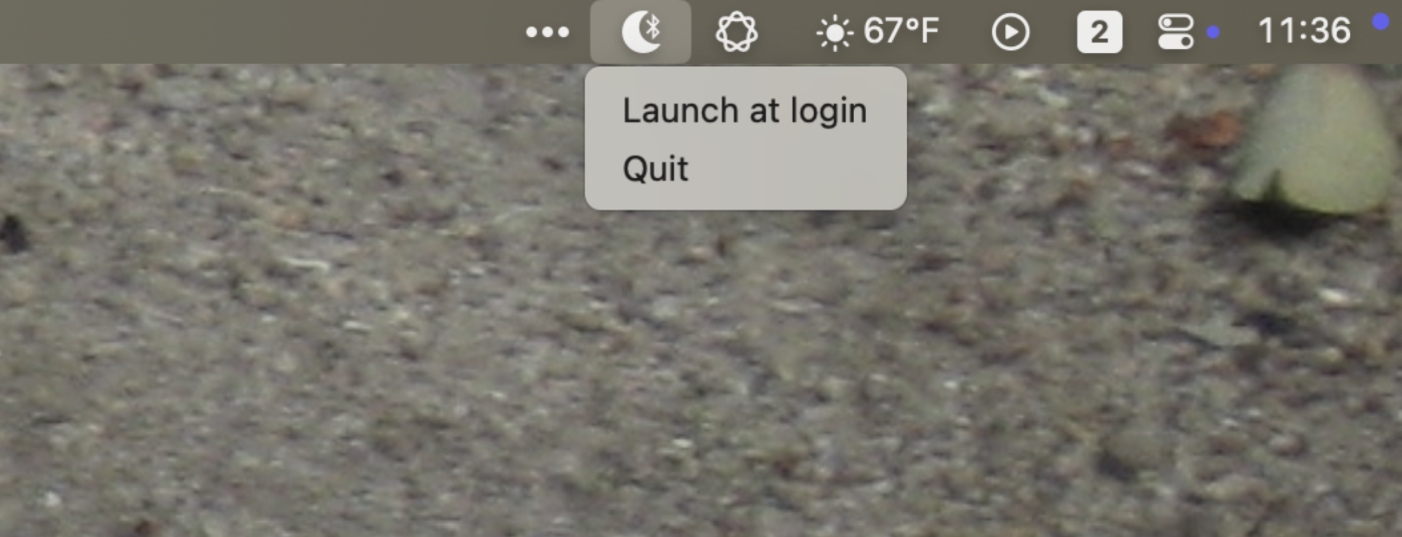 The menu bar icon for Bluesleep, which is a moon with a bluetooth icon in the cresent. The options in the menu bar iare "Launch at Login" and "Quit".